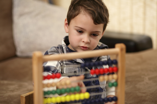 Young boy is learning basic mathematical concepts like counting, addition and subtraction.