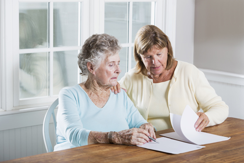 Mature woman (60s) helping elderly mother (90s) with paperwork.Mature woman (60s) helping elderly mother (90s) with paperwork.