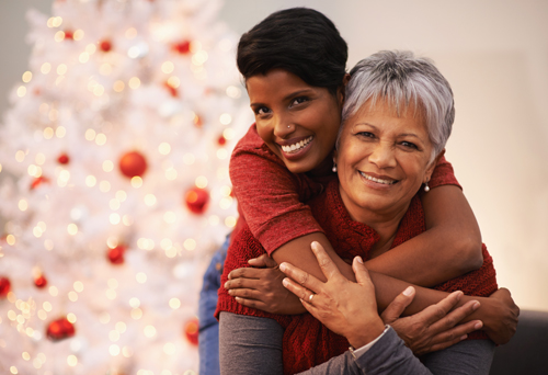 A senior woman receiving a hug from her daughter on Christmas