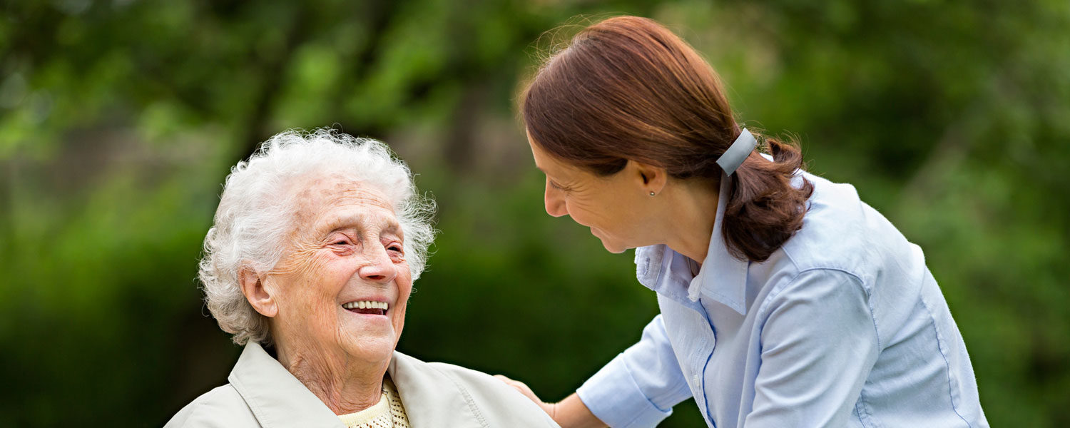Caregiver and elderly woman talking and smiling
