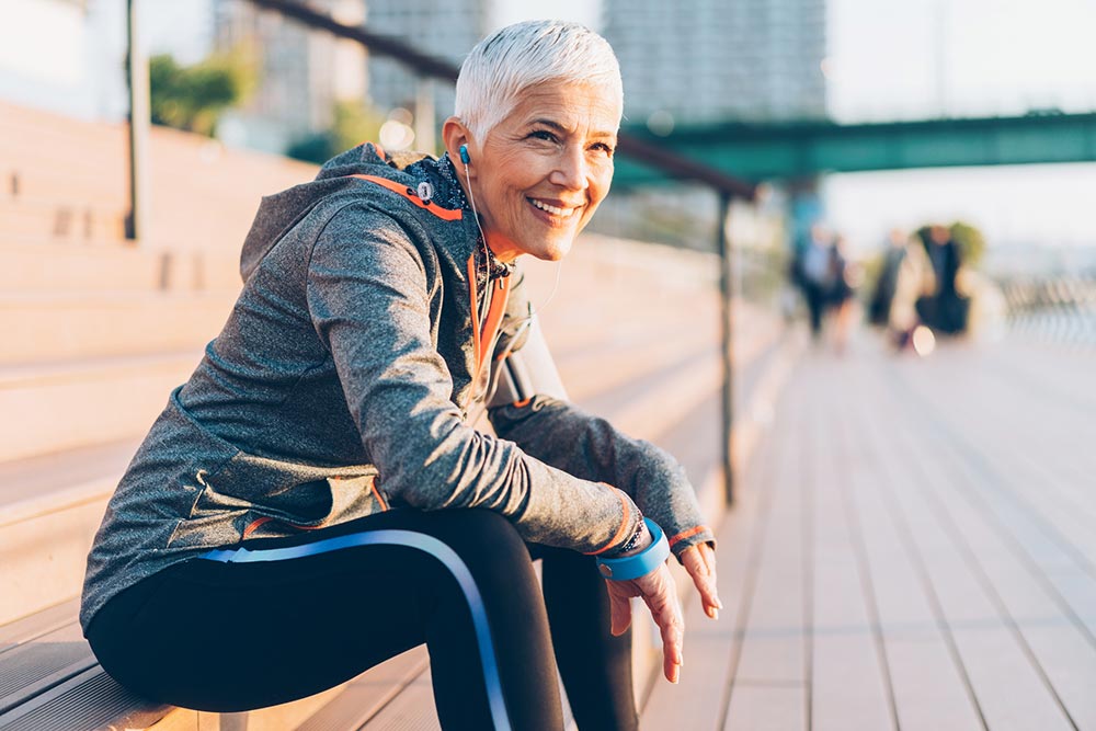 senior woman sitting on steps of building after working out outdoors