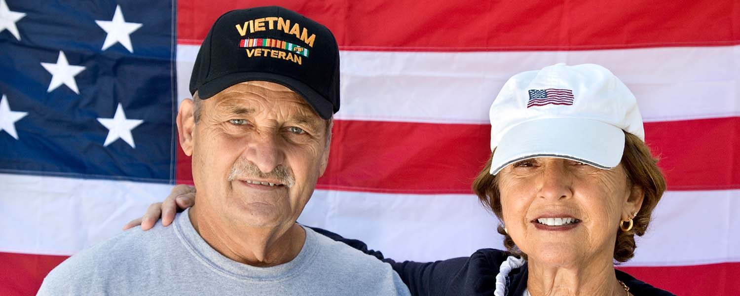veteran and his wife standing in front of an American flag