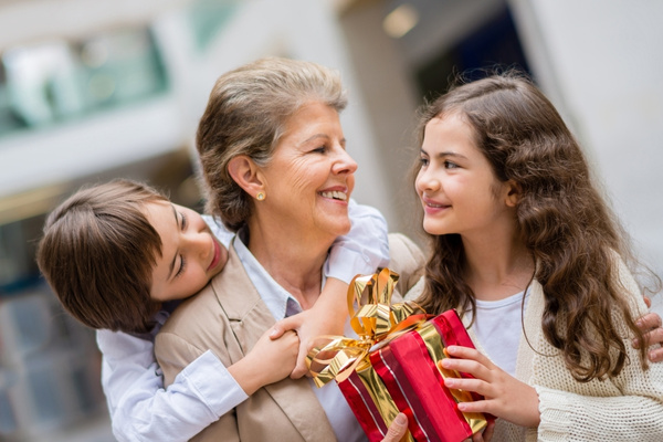 grandmother with two grandchildren boy and girl exchanging gifts