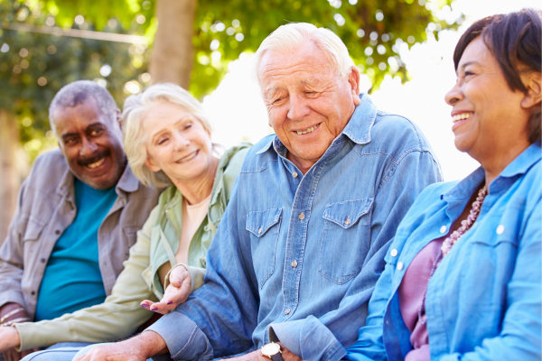 group of older adults sitting outdoors smiling and laughing together during sunset in springtime