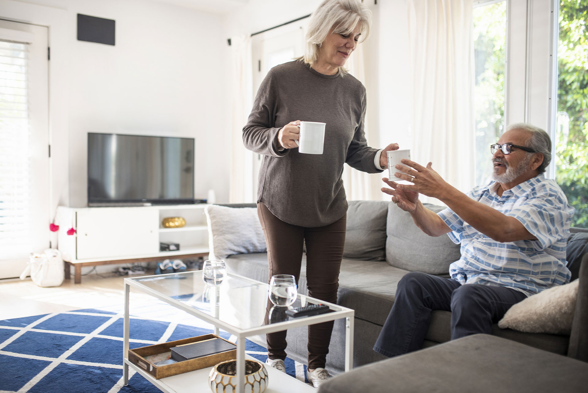 Woman serving coffee to a man in a cozy living room.