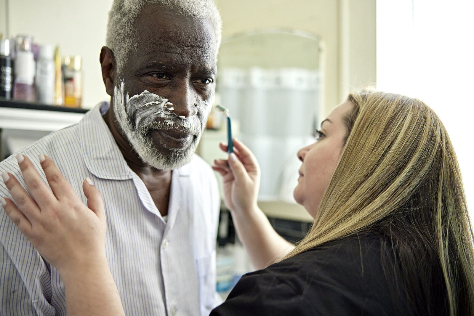 Healthcare worker helping senior client with shaving