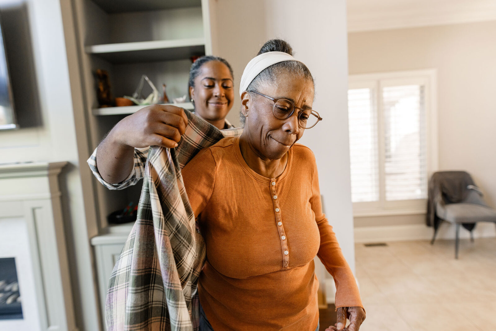 Caregiver helping to dress up senior women